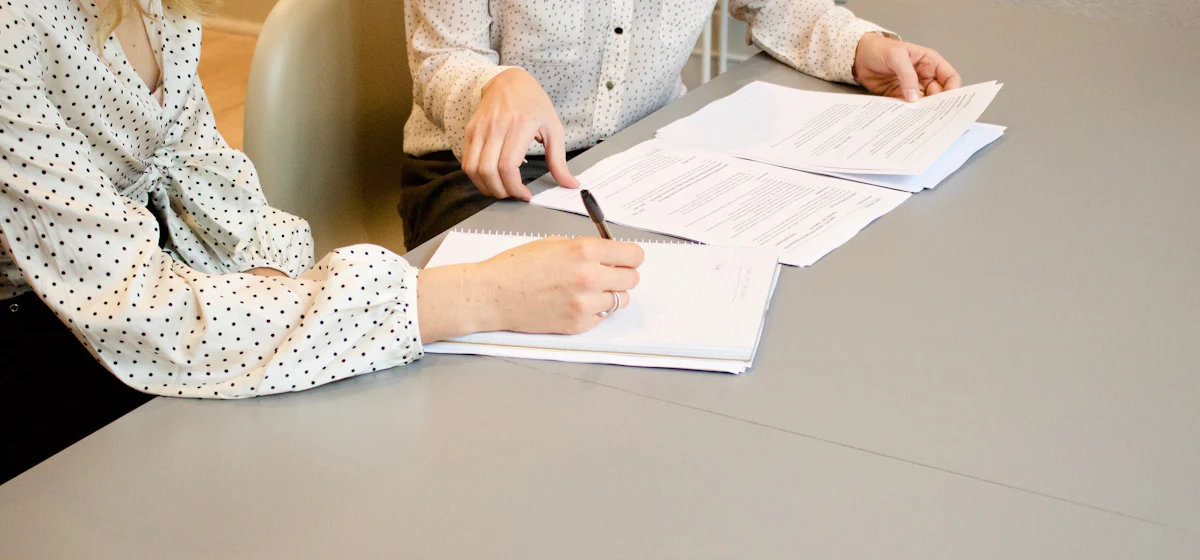 Dos personas revisando y firmando documentos sobre una mesa